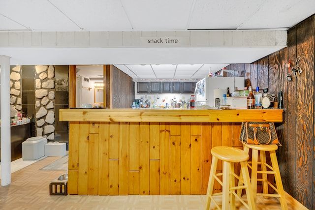 bar featuring white refrigerator, wooden walls, and light parquet floors