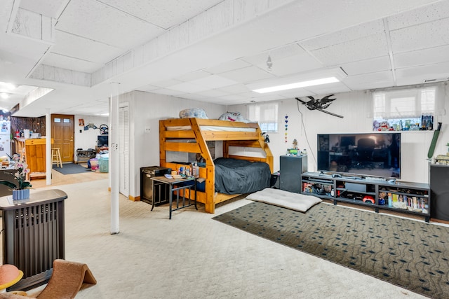 bedroom featuring a drop ceiling and light carpet