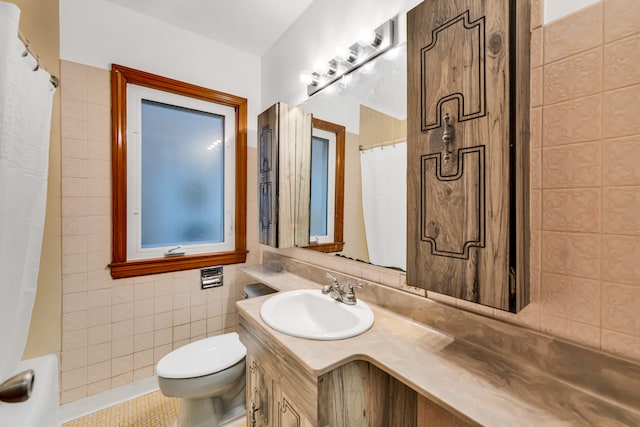 bathroom with a shower with shower curtain, vanity, tile patterned floors, toilet, and tile walls