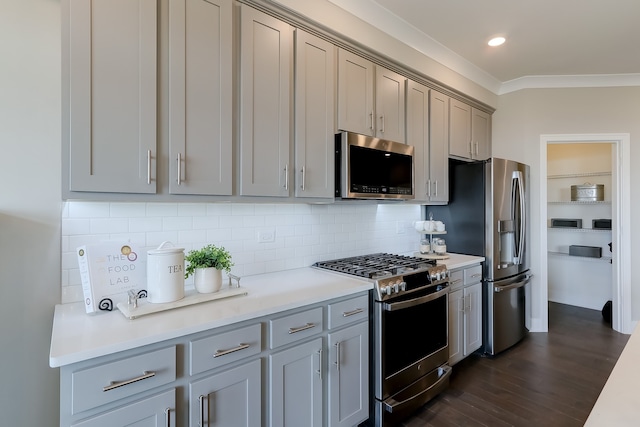 kitchen featuring stainless steel appliances, tasteful backsplash, gray cabinetry, and dark hardwood / wood-style flooring