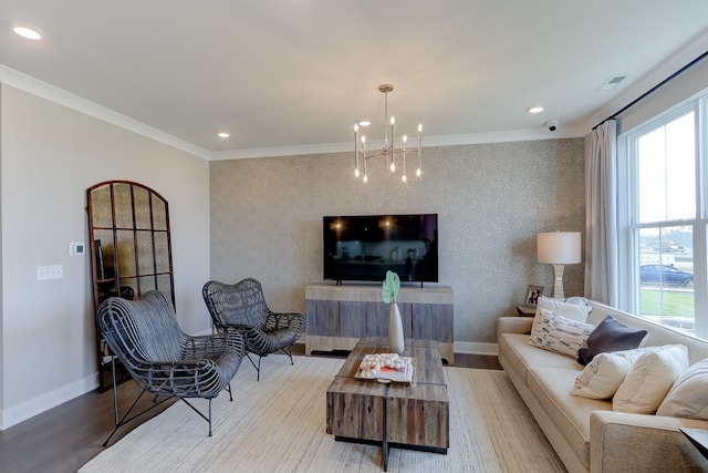 living room with ornamental molding, a wealth of natural light, a notable chandelier, and hardwood / wood-style flooring