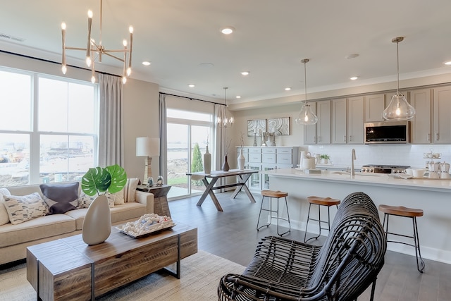 living room featuring an inviting chandelier, sink, and light wood-type flooring