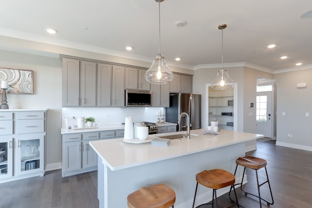 kitchen with an island with sink, stainless steel appliances, sink, and a breakfast bar