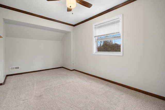 empty room with lofted ceiling, ceiling fan, crown molding, and carpet floors