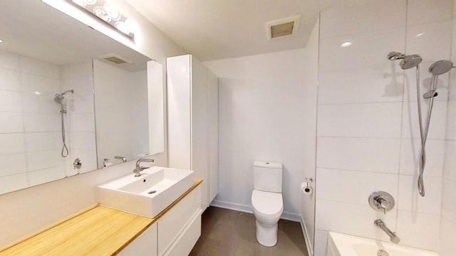 full bathroom with hardwood / wood-style flooring, vanity, tiled shower / bath combo, and toilet