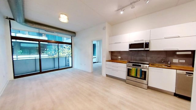 kitchen with light wood-type flooring, white cabinetry, stainless steel appliances, and tasteful backsplash