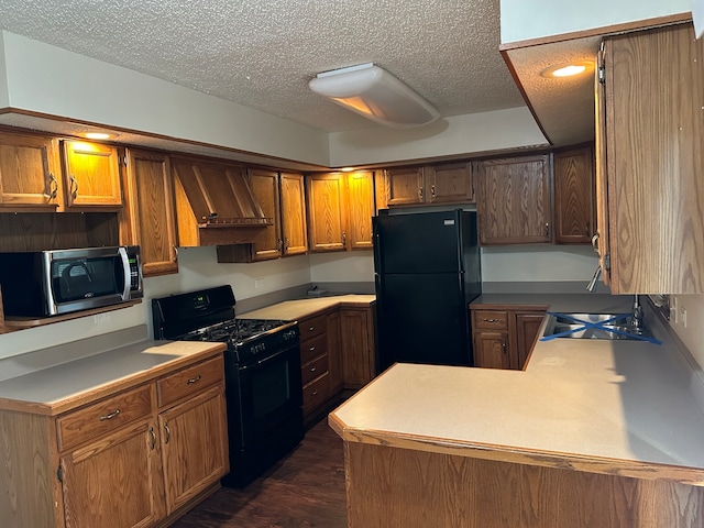 kitchen with a textured ceiling, black appliances, dark hardwood / wood-style floors, and sink