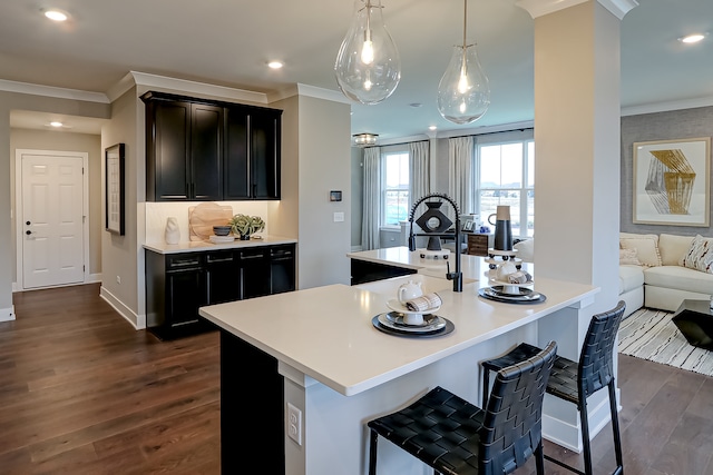 kitchen with a breakfast bar area, dark hardwood / wood-style floors, and ornamental molding