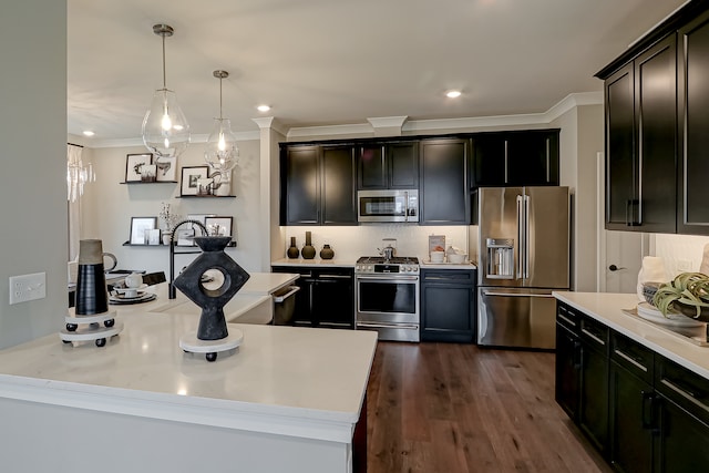 kitchen featuring stainless steel appliances, hanging light fixtures, a kitchen island, crown molding, and dark wood-type flooring