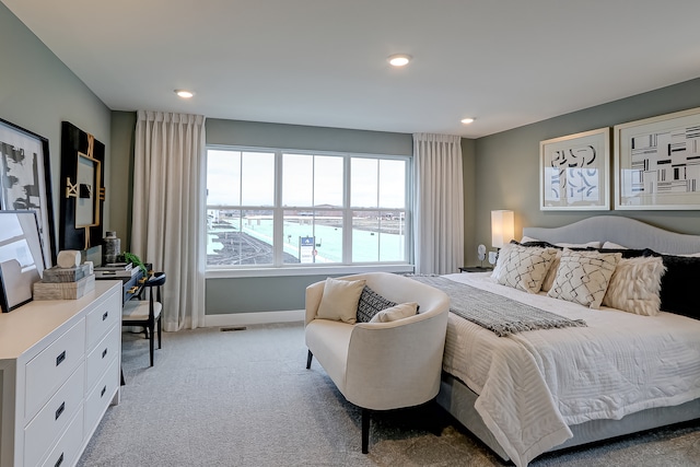 bedroom with a water view and light carpet