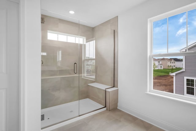 bathroom with a wealth of natural light, an enclosed shower, and tile patterned flooring