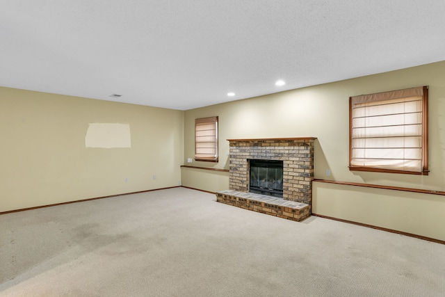 unfurnished living room featuring light carpet, a textured ceiling, and a brick fireplace