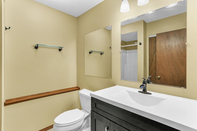 bathroom featuring a shower, vanity, a textured ceiling, and toilet