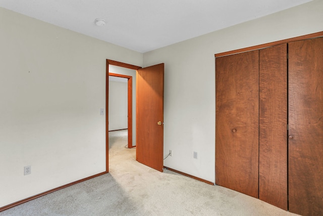 unfurnished bedroom featuring light carpet and a closet