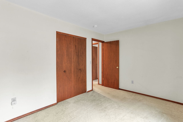 unfurnished bedroom featuring a closet and light colored carpet