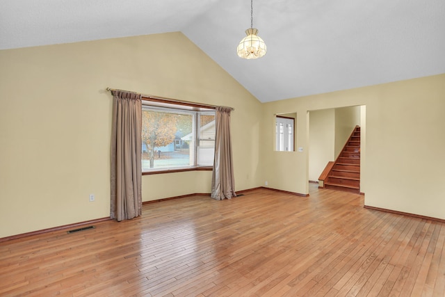 empty room with light hardwood / wood-style floors, high vaulted ceiling, and a notable chandelier