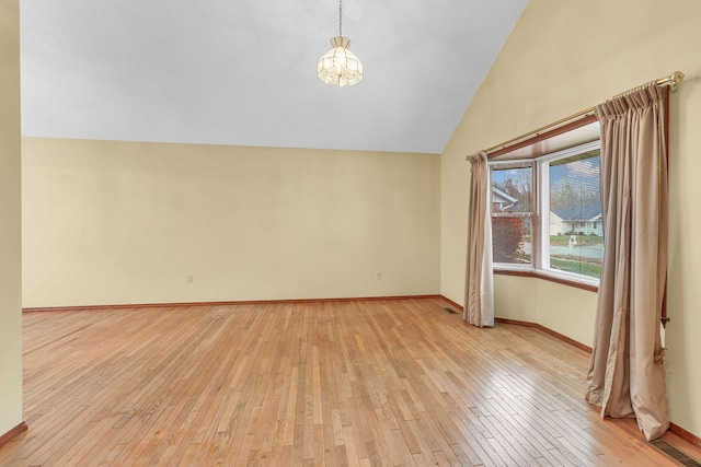 unfurnished room featuring a chandelier, high vaulted ceiling, and light hardwood / wood-style floors