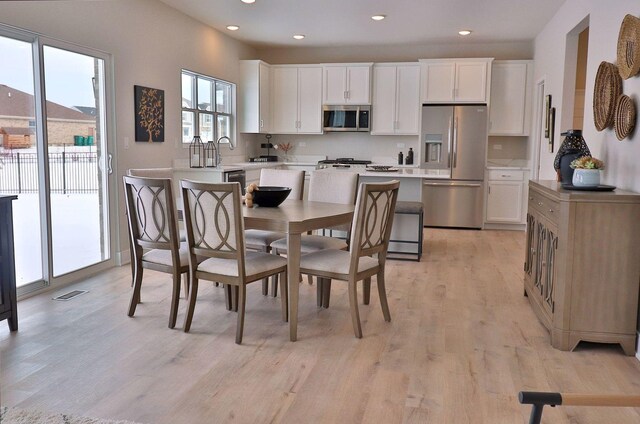 kitchen featuring light hardwood / wood-style floors, a center island, white cabinets, and appliances with stainless steel finishes