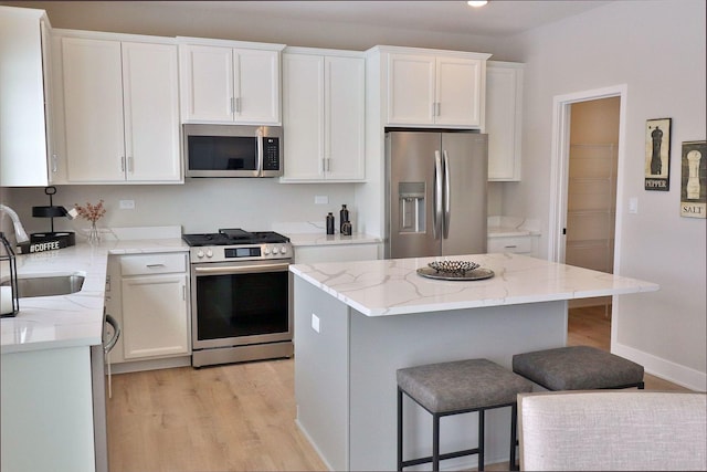 kitchen featuring sink, appliances with stainless steel finishes, a center island, white cabinets, and light wood-type flooring