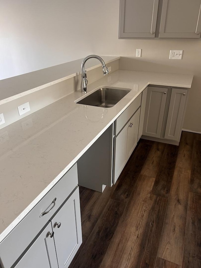 kitchen featuring light stone counters, dark hardwood / wood-style floors, gray cabinets, and sink