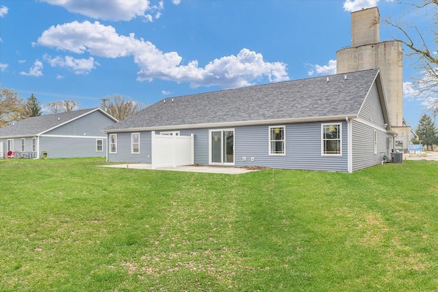 rear view of house with cooling unit, a patio, and a lawn