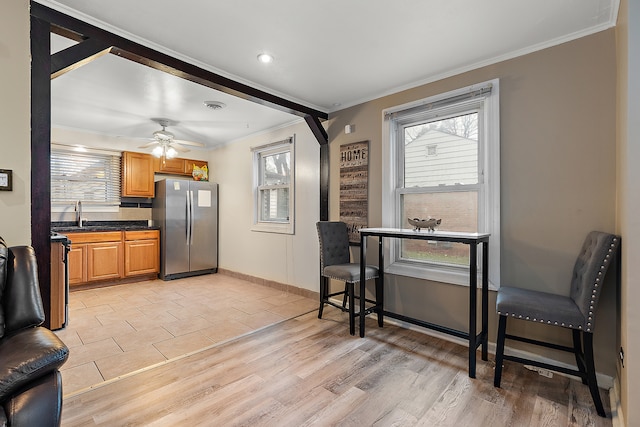 kitchen with appliances with stainless steel finishes, light hardwood / wood-style floors, ceiling fan, and crown molding