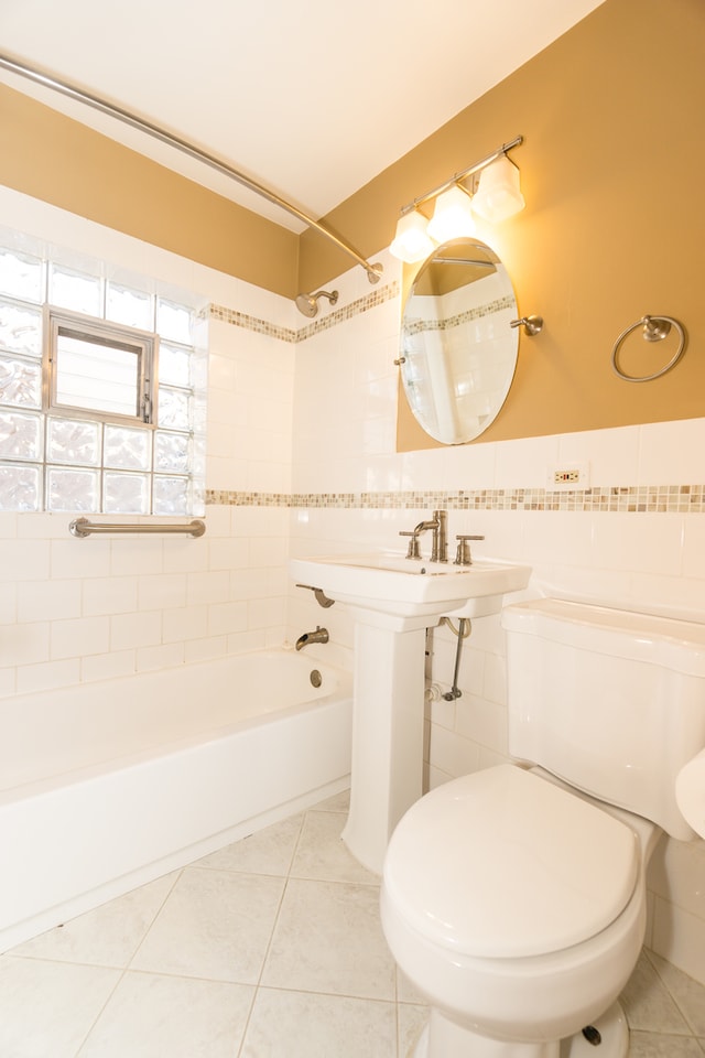 bathroom featuring tile walls, toilet, tiled shower / bath, and tile patterned floors