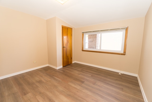 empty room featuring hardwood / wood-style floors and vaulted ceiling