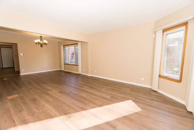 empty room featuring a chandelier and wood-type flooring