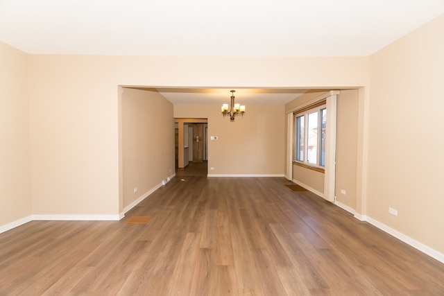 spare room with a chandelier and hardwood / wood-style floors