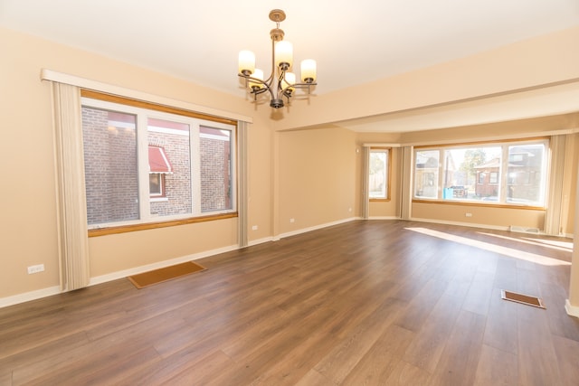 empty room with dark hardwood / wood-style flooring and an inviting chandelier