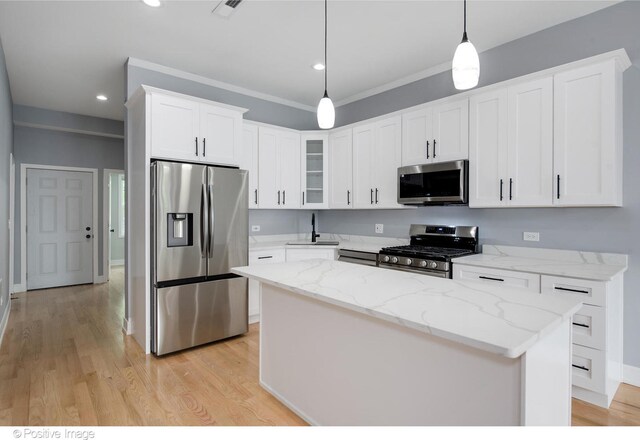 kitchen featuring light hardwood / wood-style floors, white cabinetry, appliances with stainless steel finishes, hanging light fixtures, and a center island