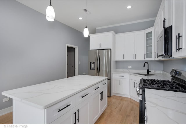 kitchen with stainless steel appliances, white cabinetry, sink, and decorative light fixtures