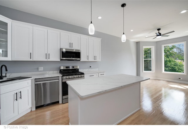 kitchen with stainless steel appliances, white cabinetry, light hardwood / wood-style flooring, and a center island