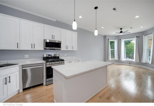 kitchen featuring stainless steel appliances, light hardwood / wood-style floors, hanging light fixtures, a kitchen island, and white cabinets