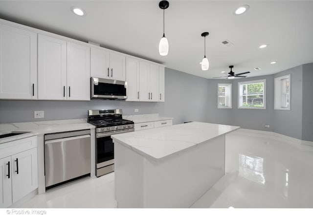 kitchen featuring a kitchen island, white cabinetry, appliances with stainless steel finishes, and light stone countertops