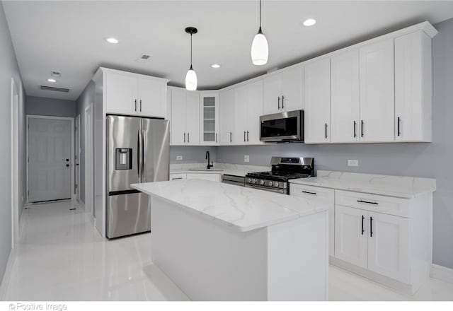 kitchen with stainless steel appliances, white cabinetry, pendant lighting, sink, and a center island