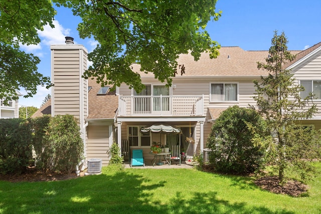 back of property with central air condition unit, a lawn, and a balcony