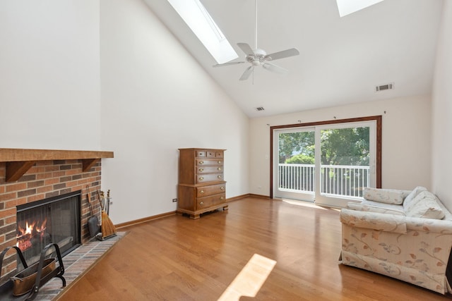 living room with ceiling fan, high vaulted ceiling, a skylight, a fireplace, and wood-type flooring