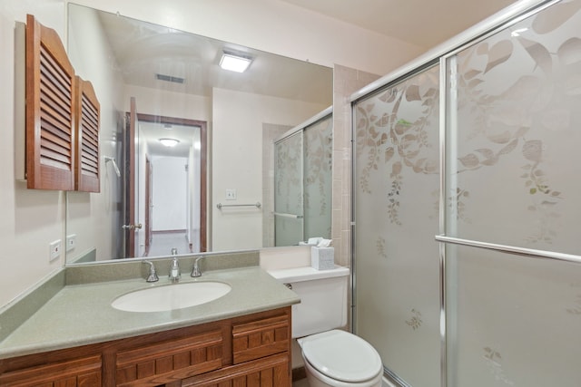 bathroom with toilet, vanity, and a shower with door