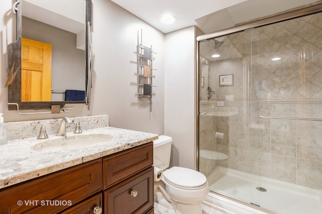 bathroom featuring vanity, a shower with shower door, and toilet