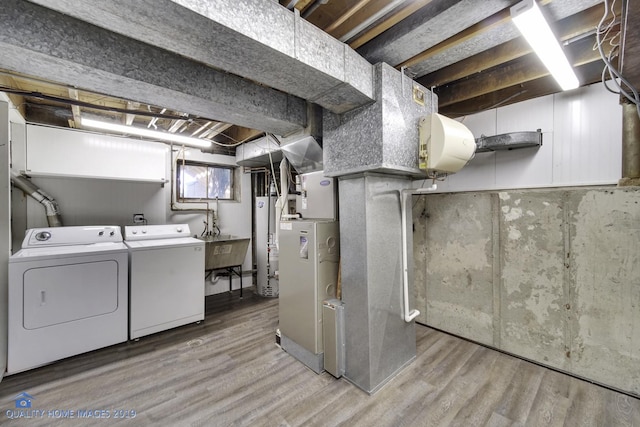 laundry area featuring sink, light hardwood / wood-style floors, washer and clothes dryer, and water heater