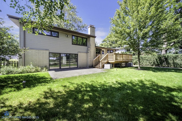 rear view of house featuring a wooden deck, a yard, and a patio