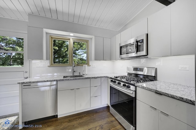 kitchen featuring light stone countertops, stainless steel appliances, dark wood-type flooring, sink, and white cabinets