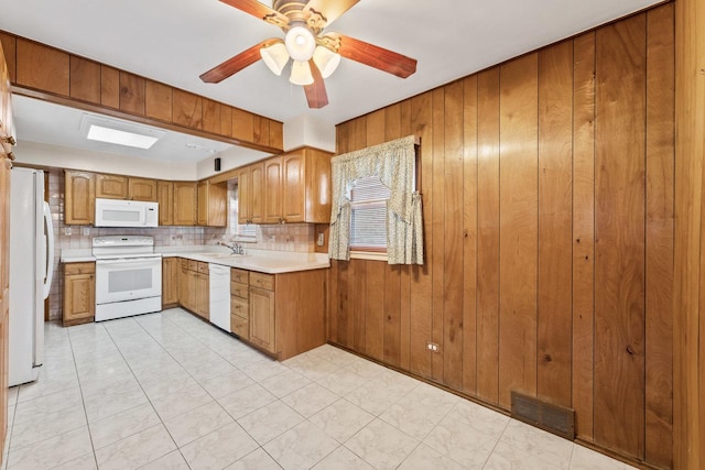 kitchen with decorative backsplash, white appliances, ceiling fan, and wood walls