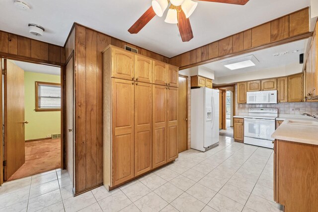 kitchen featuring ceiling fan, sink, backsplash, white appliances, and wooden walls