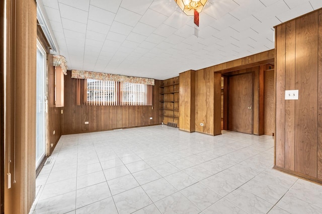 spare room with built in shelves and wooden walls