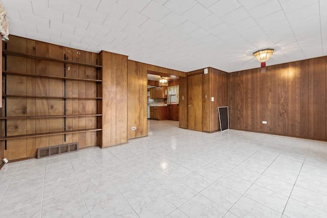 unfurnished living room with built in shelves and wooden walls