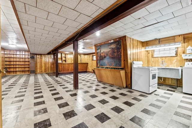 basement with wood walls, washer / dryer, and sink