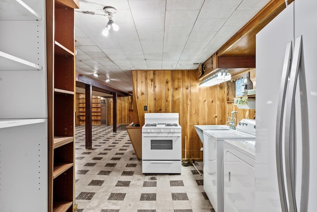 laundry area with separate washer and dryer and wood walls